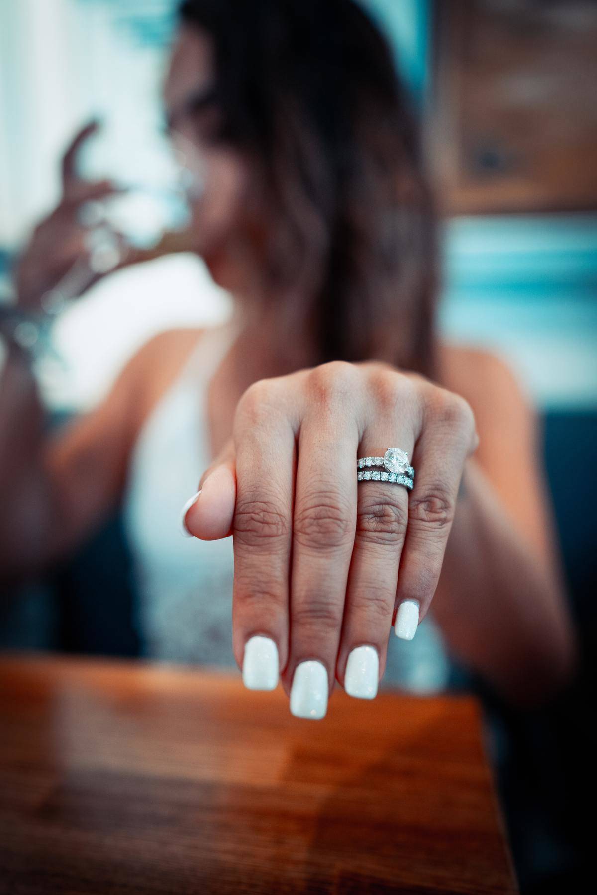 Woman holding up hand wearing engagement ring