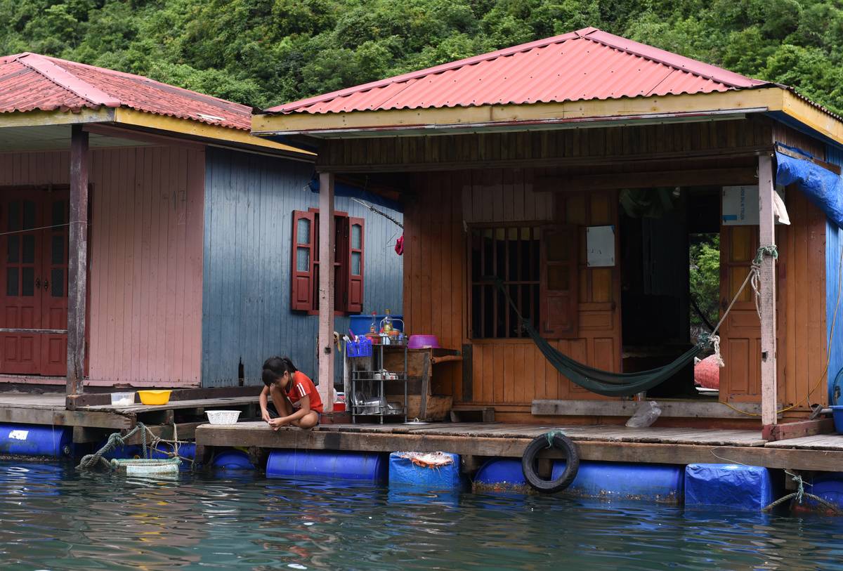 A girl fishes at the Cua Van floating village, in Halong Bay...