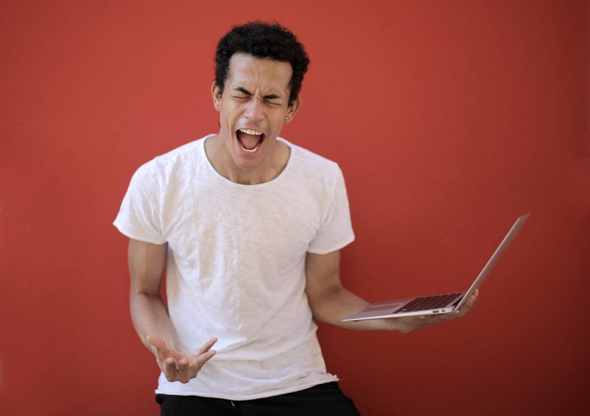 angry guy holding computer against red background