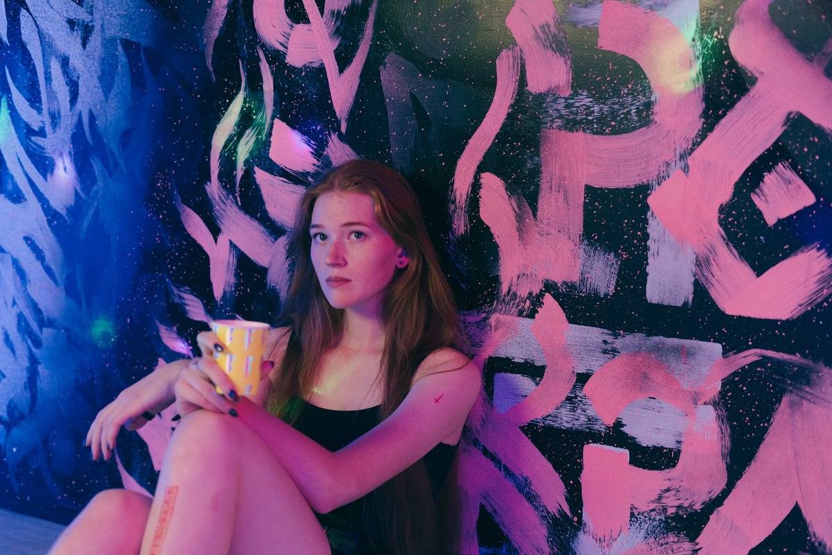 young teen girl sitting against wall holding a mug