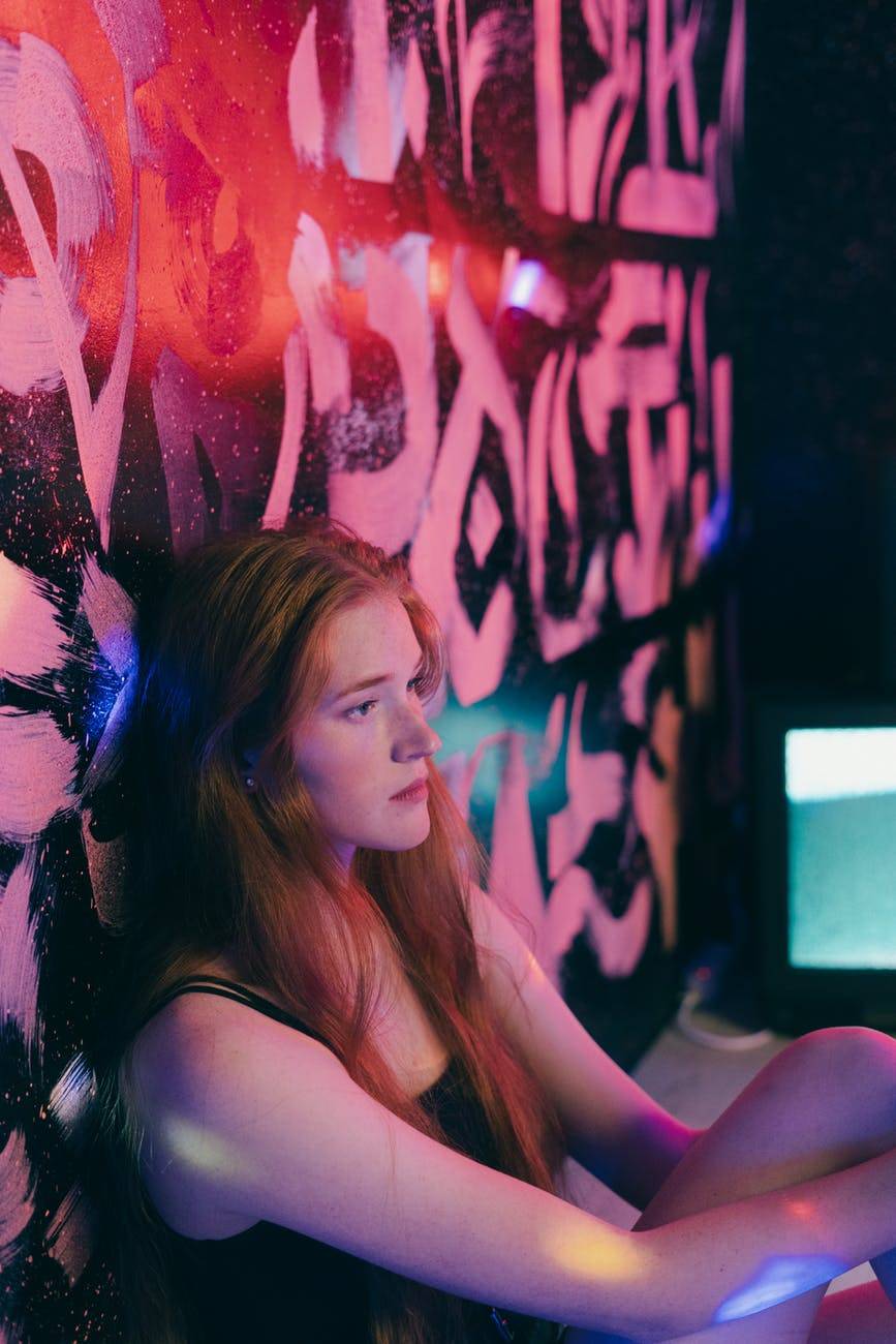 young teen girl sitting against a wall