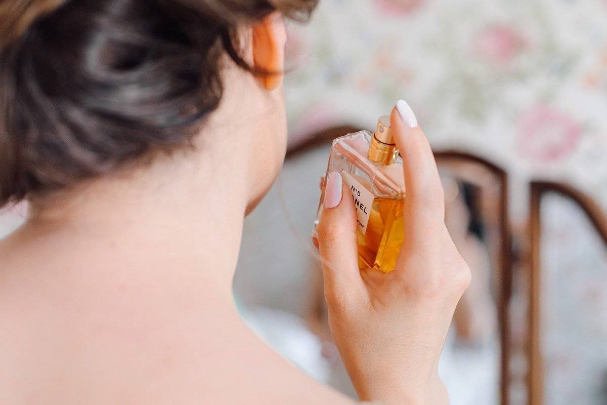 A woman sprays perfume on her neck.