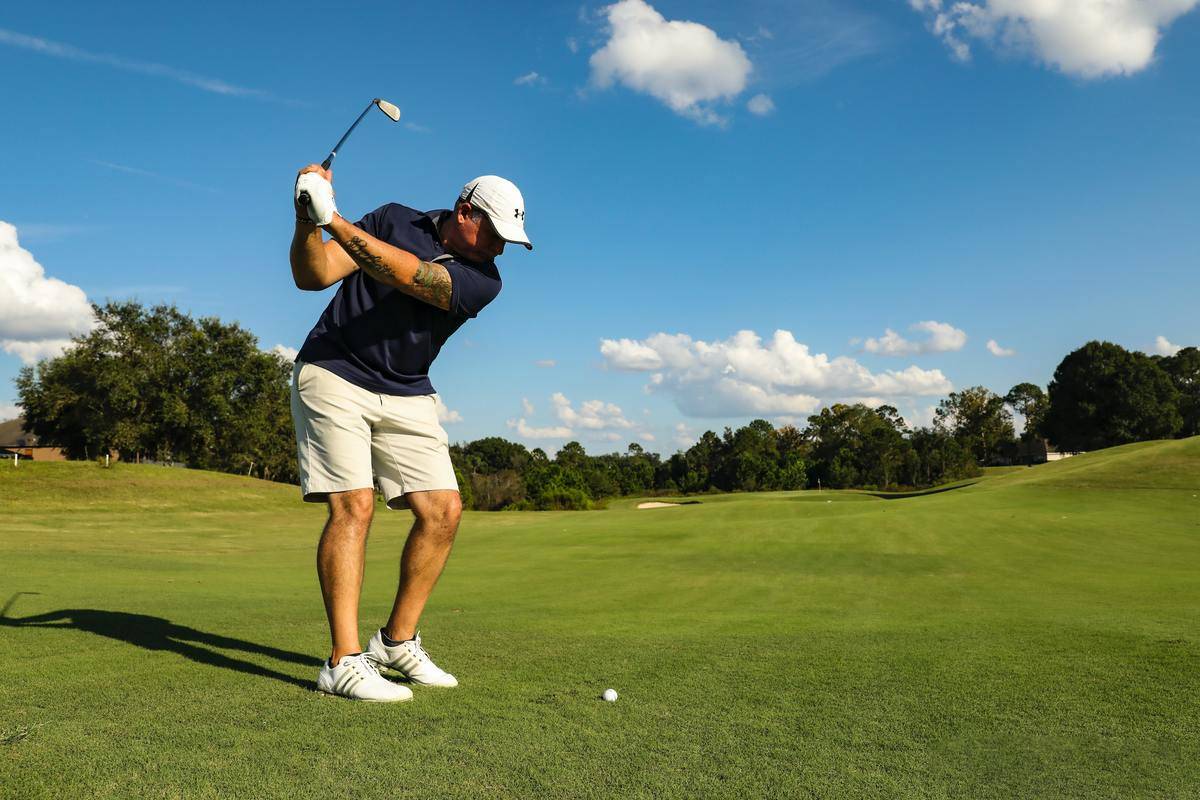 a man swinging a club to hit a golf ball at a golf course