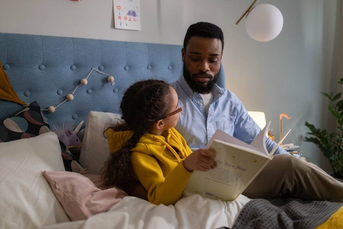 father reading to daughter in bed