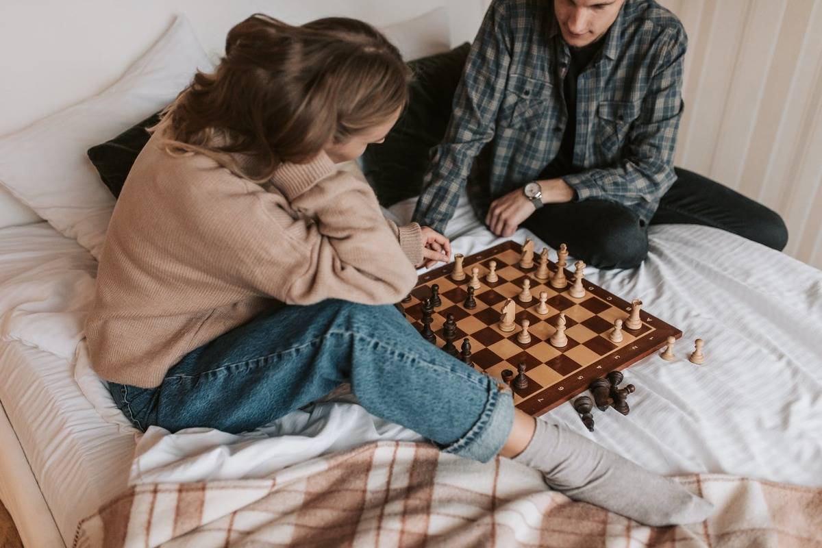 two people playing chess on a bed