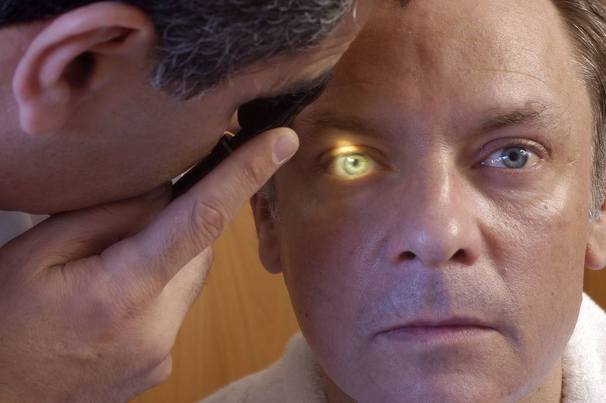 A doctor shines a light in a man's eye during an Ophthalmology Exam.