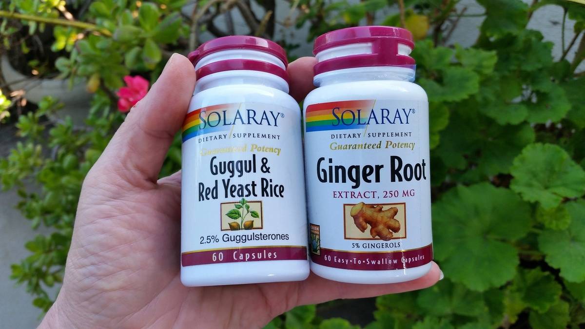 A person holds up jars of herbal supplements.