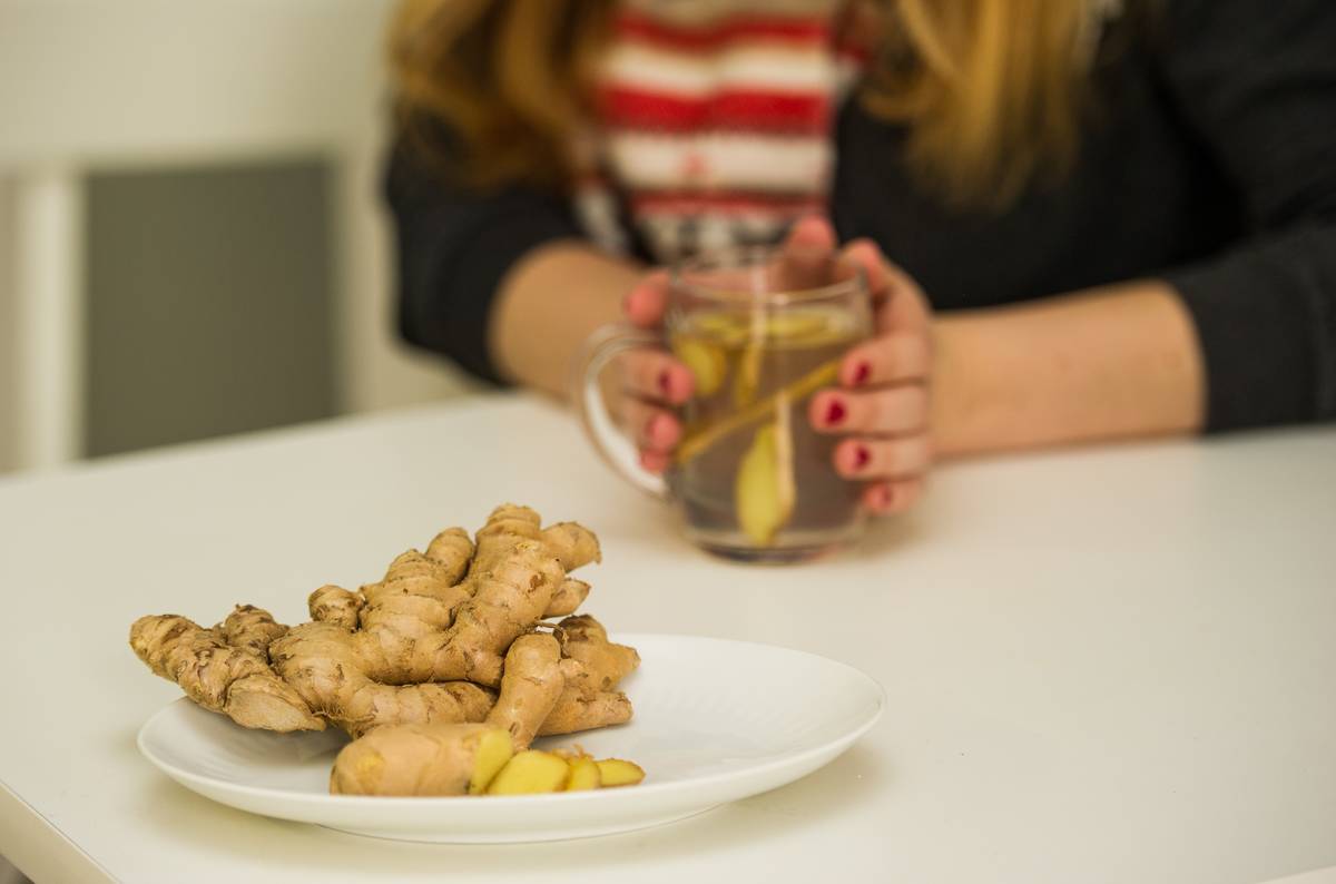 A woman drinks a tea with raw ginger to aid her cold.