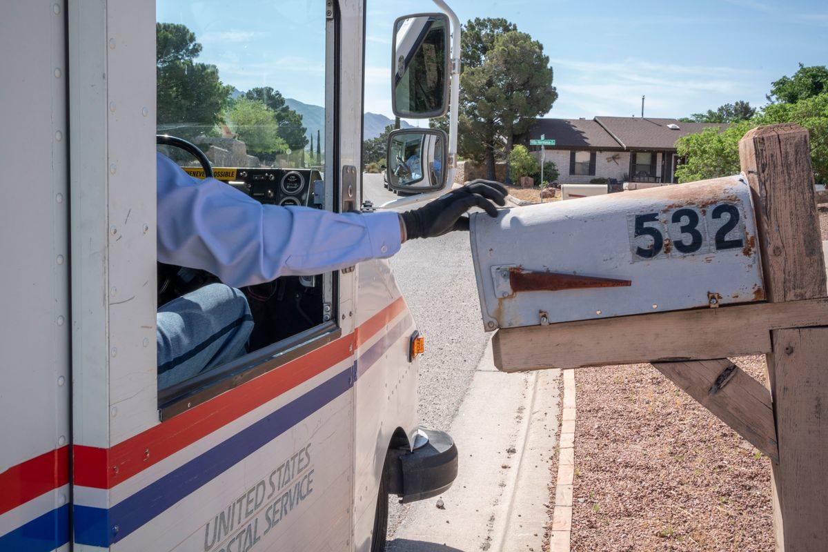 A delivery driver opens a person's mailbox.
