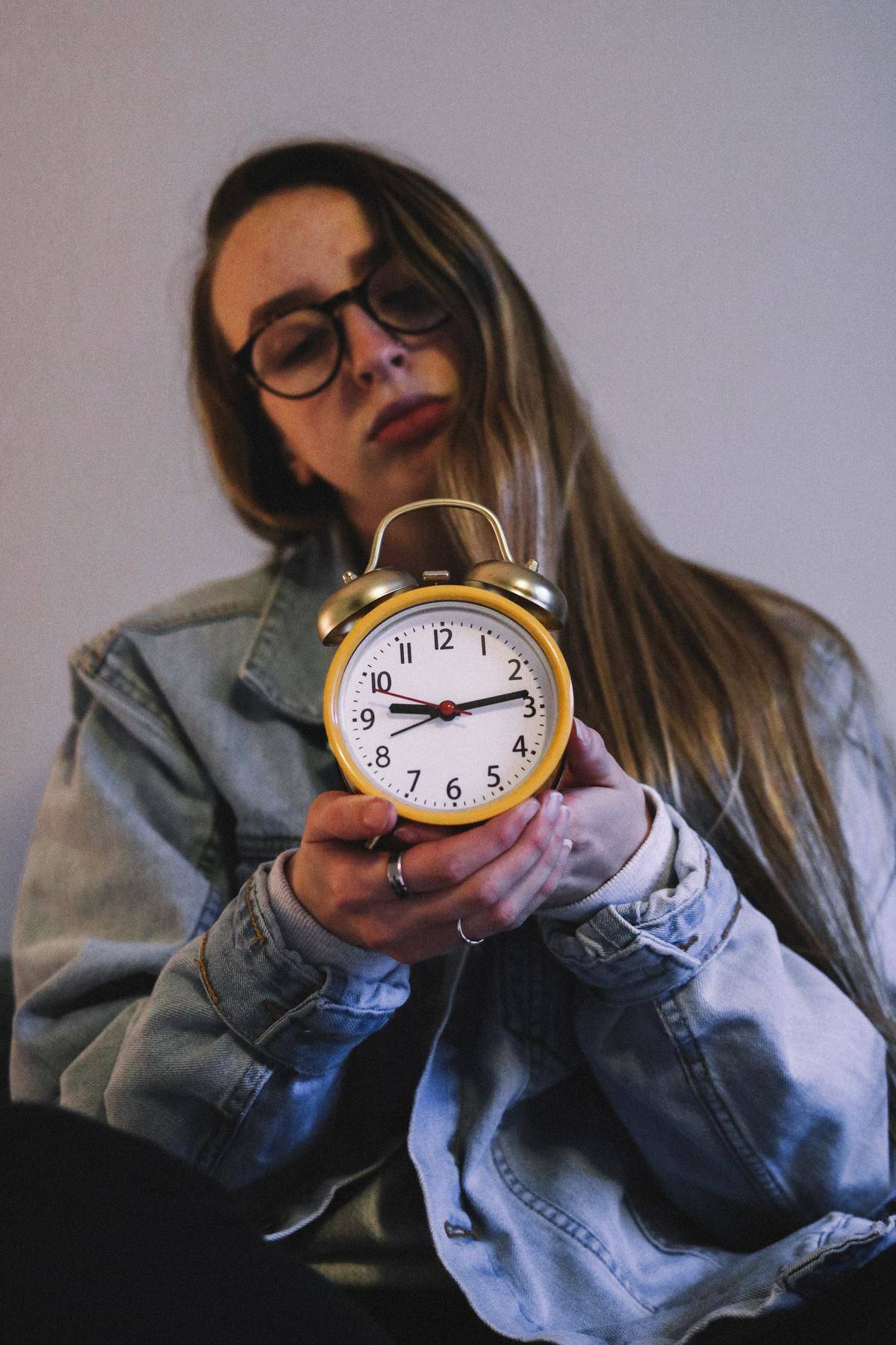 A woman holds an alarm clock.