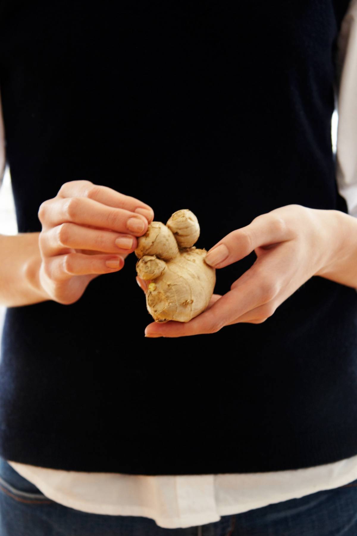 A woman holds raw ginger.