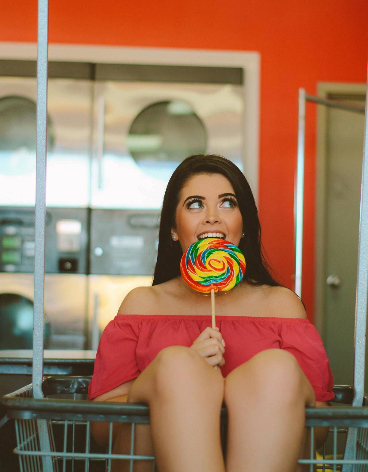 a girl eating a lollipop in a laundromat