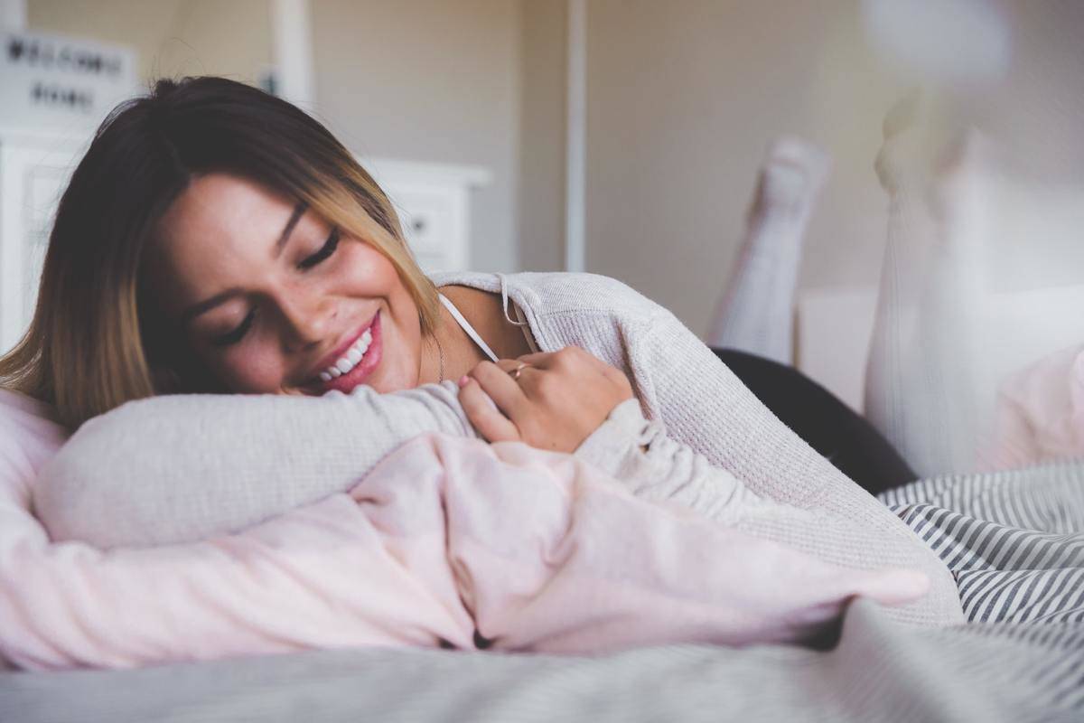A woman smiles while napping in her bed.