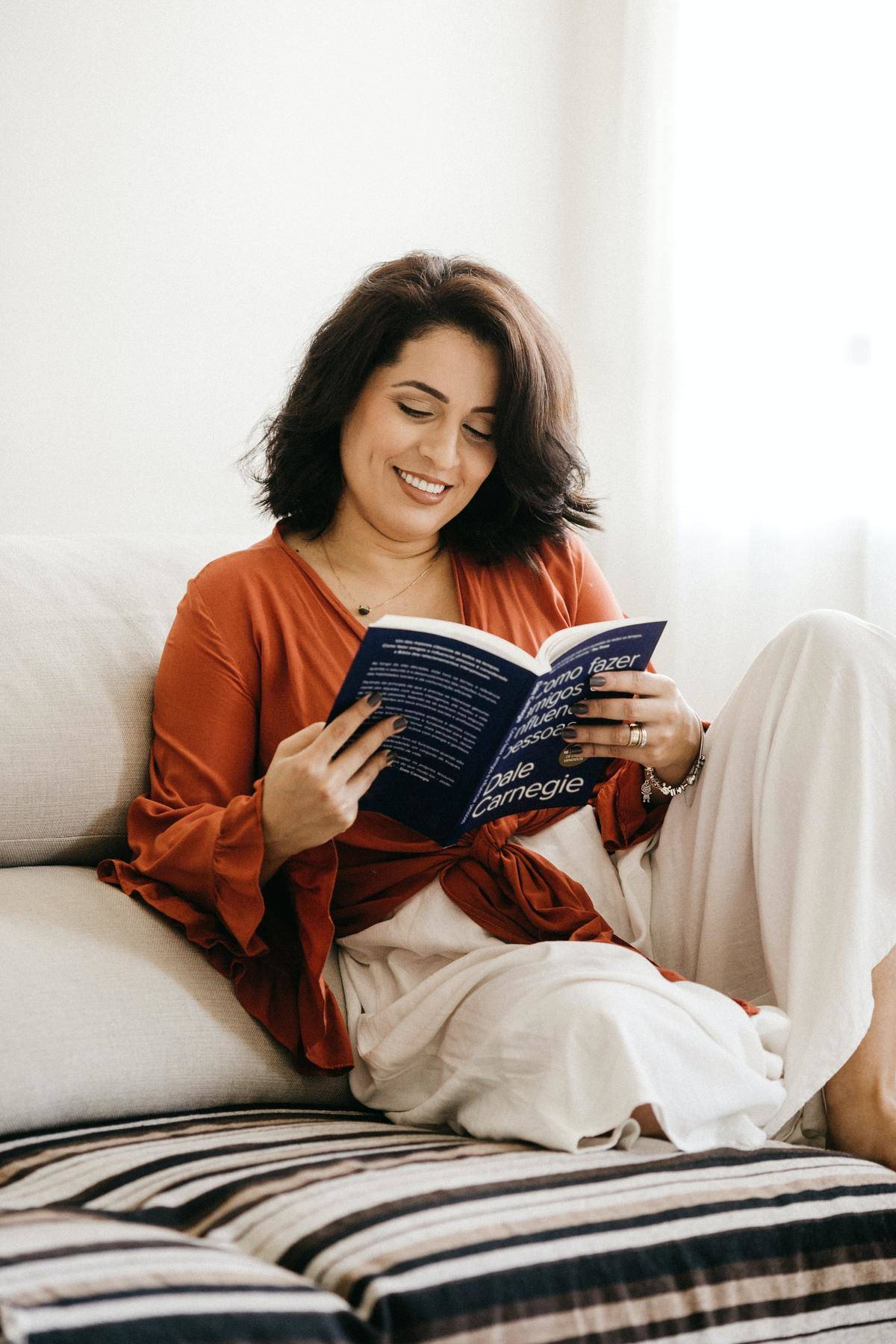 A woman smiles as she reads in bed.