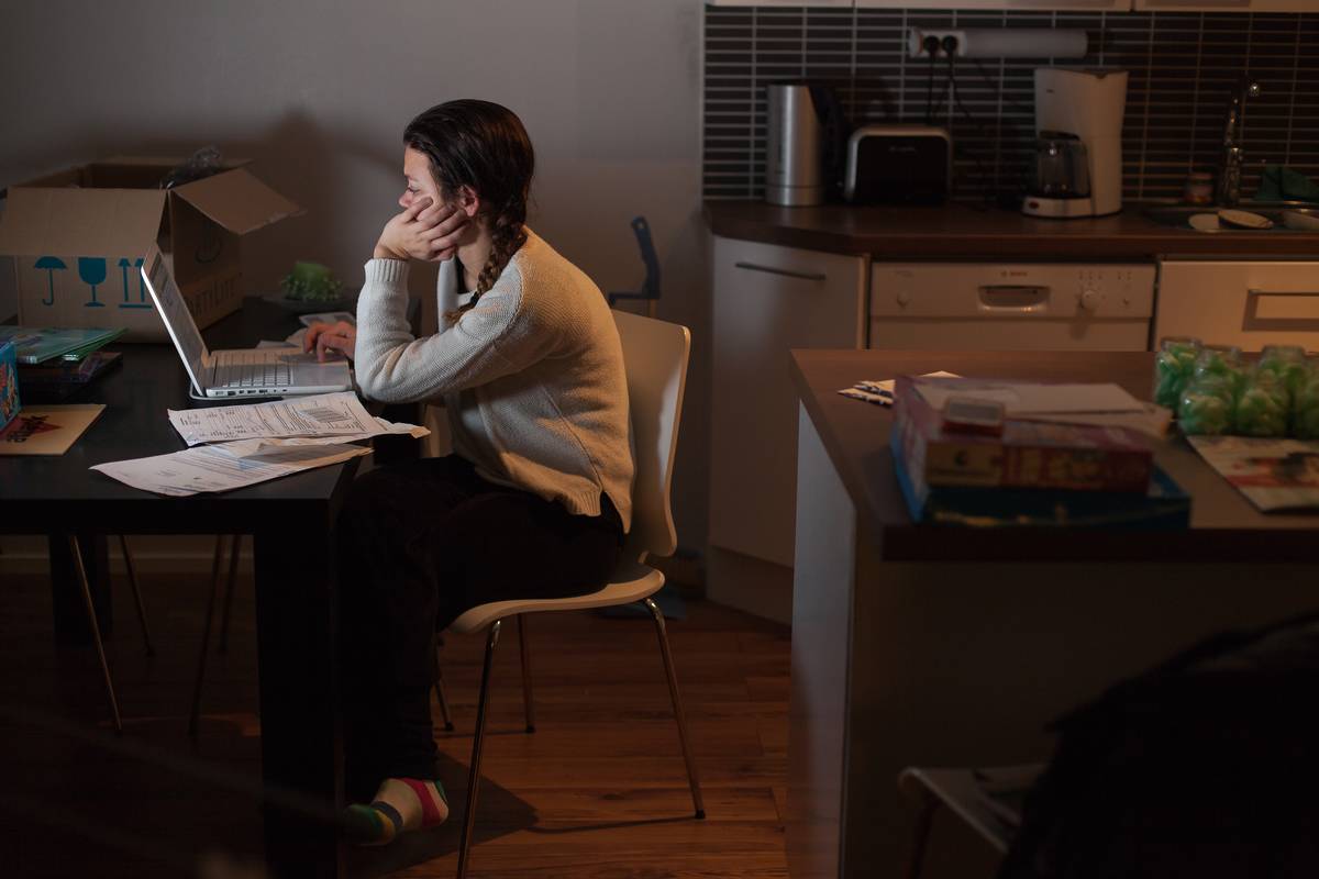 At night, a woman works on her taxes with her laptop.
