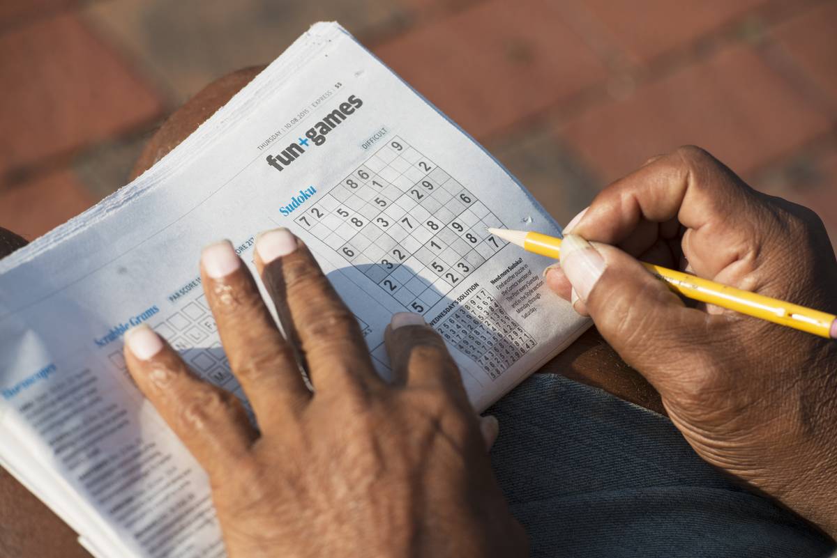 A man does a sudoku puzzle in the newspaper.