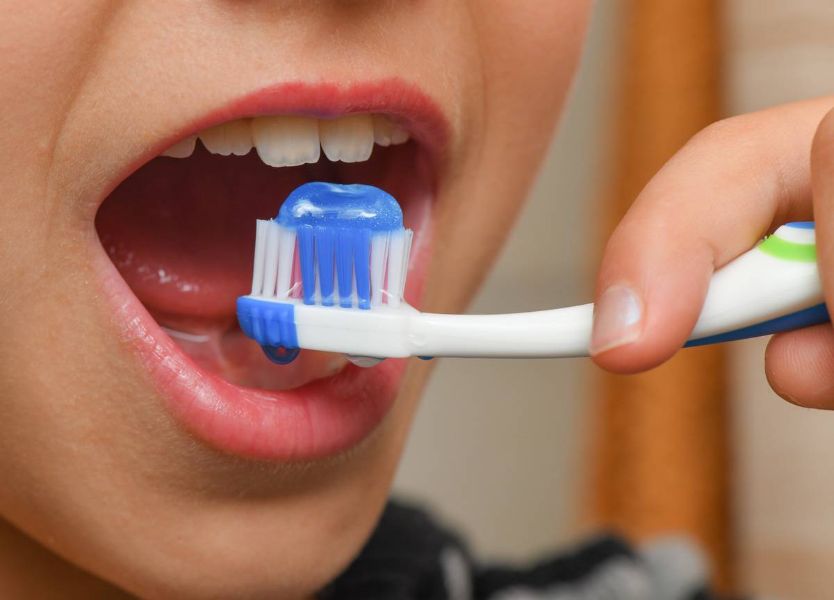 A person opens his mouth, about to brush his teeth.