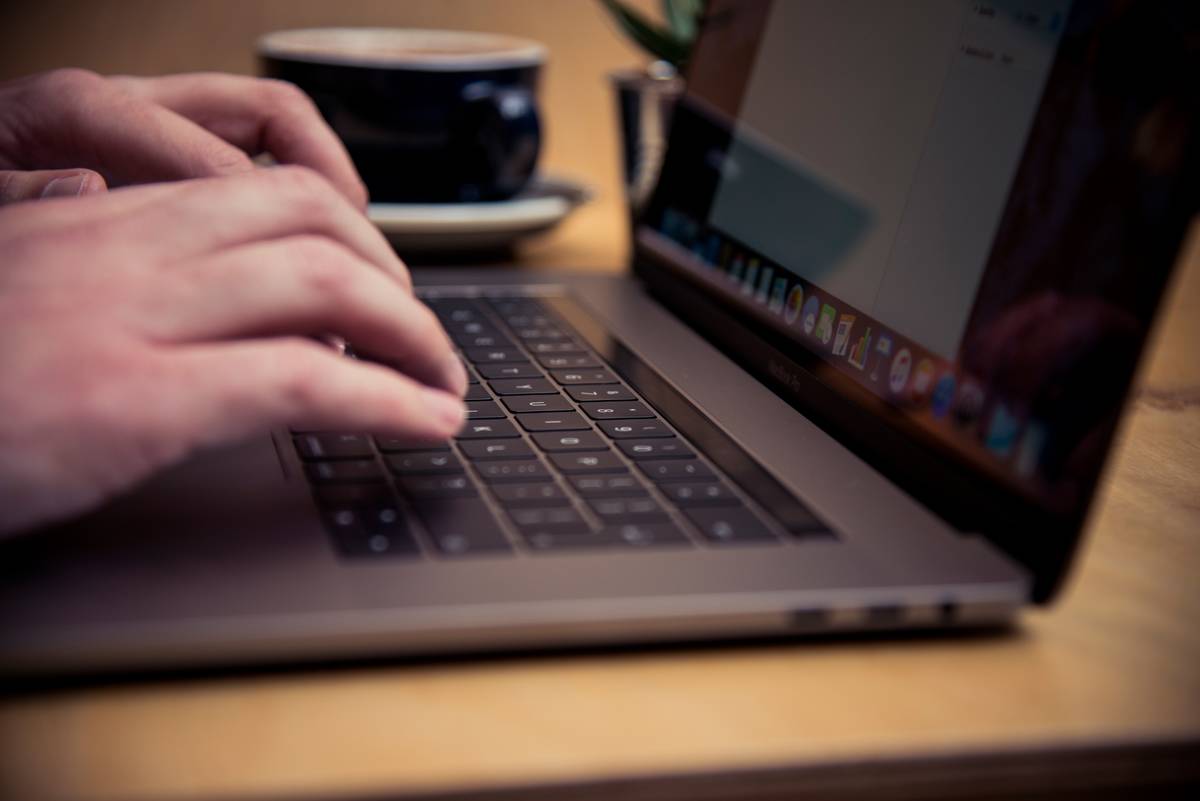 A person types on his laptop at a cafe.