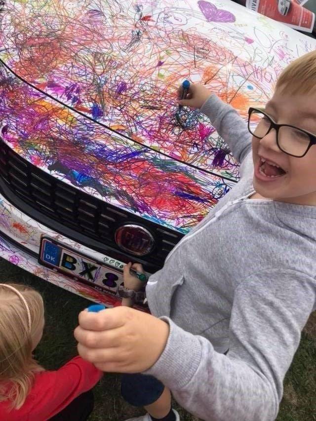 Kids drawing on the hood of a car. 