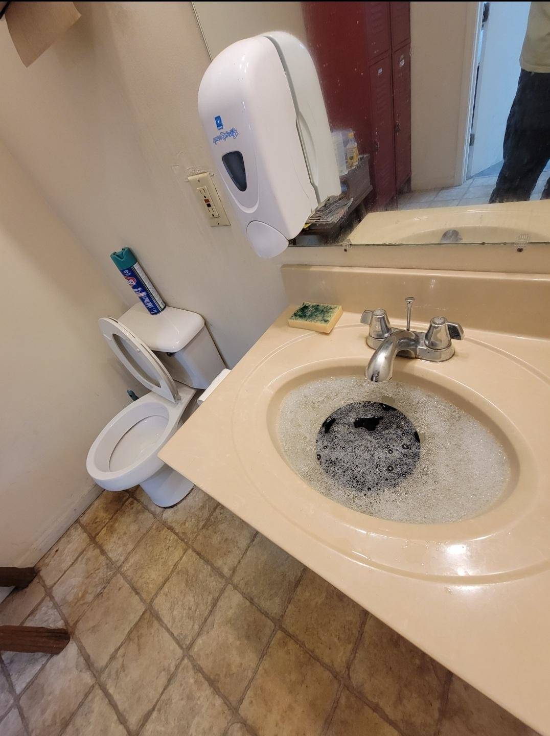 Bathroom sink filled with soapy water and plate soaking