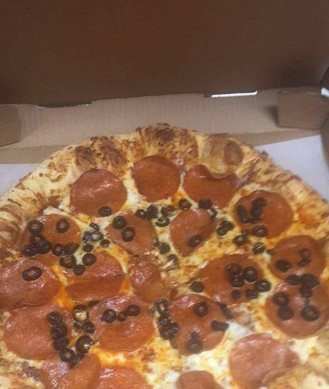'happy birthday' poorly spelt out in olives on pizza