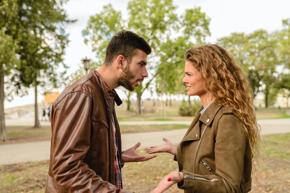 Couple stands outside in a park and fight with each other. 