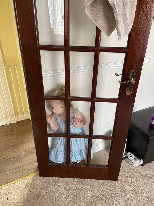 Child hiding behind a glass door during hide and seek.