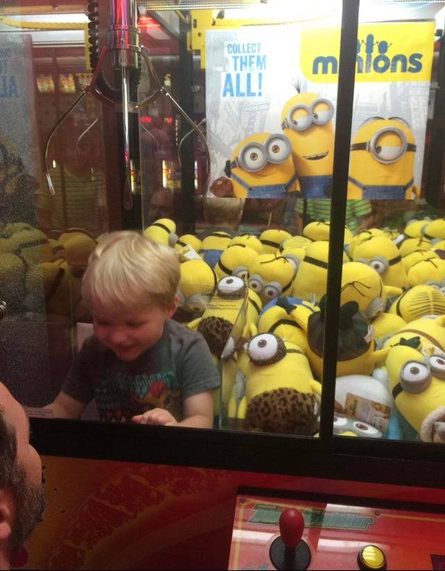 Kid stuck in a claw game amongst stuffed minions. 