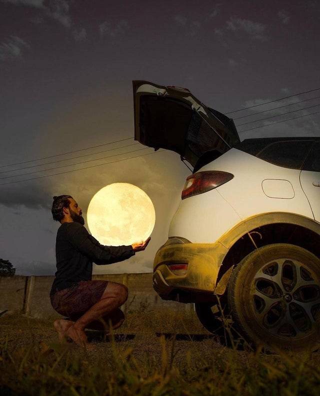Perspective photography makes it look like man is holding moon next to car