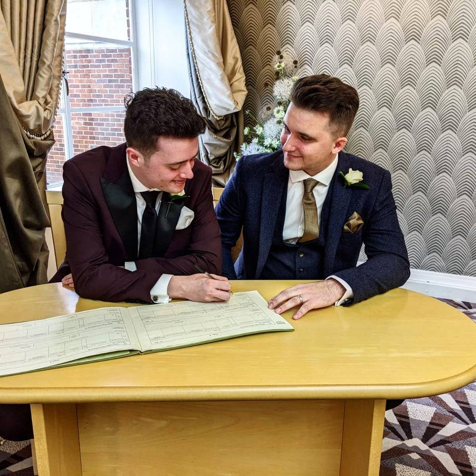 Newlywed couple sign their marriage license and look at each other lovingly. 