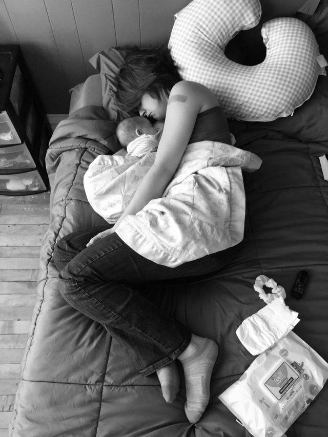 Back and white photo of a mom sleeping on the bed next to her baby