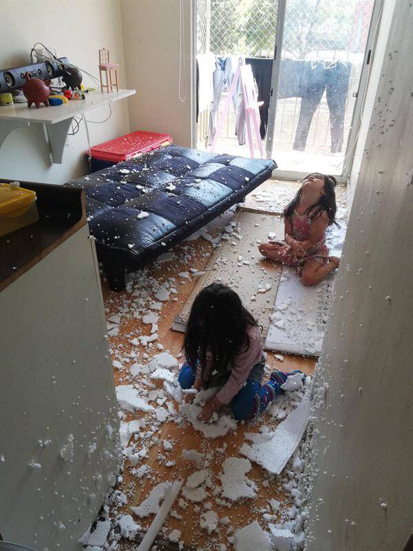 Two kids have broken up styrofoam and made a big mess.
