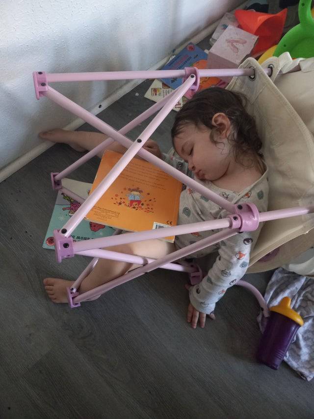 Child asleep underneath a chair.