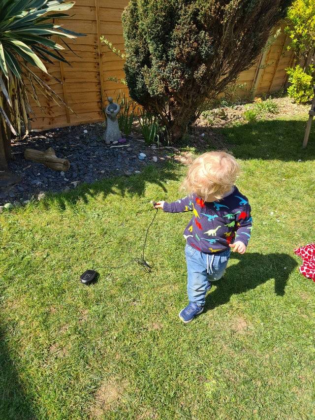 Child pulling computer mouse in the grass. 