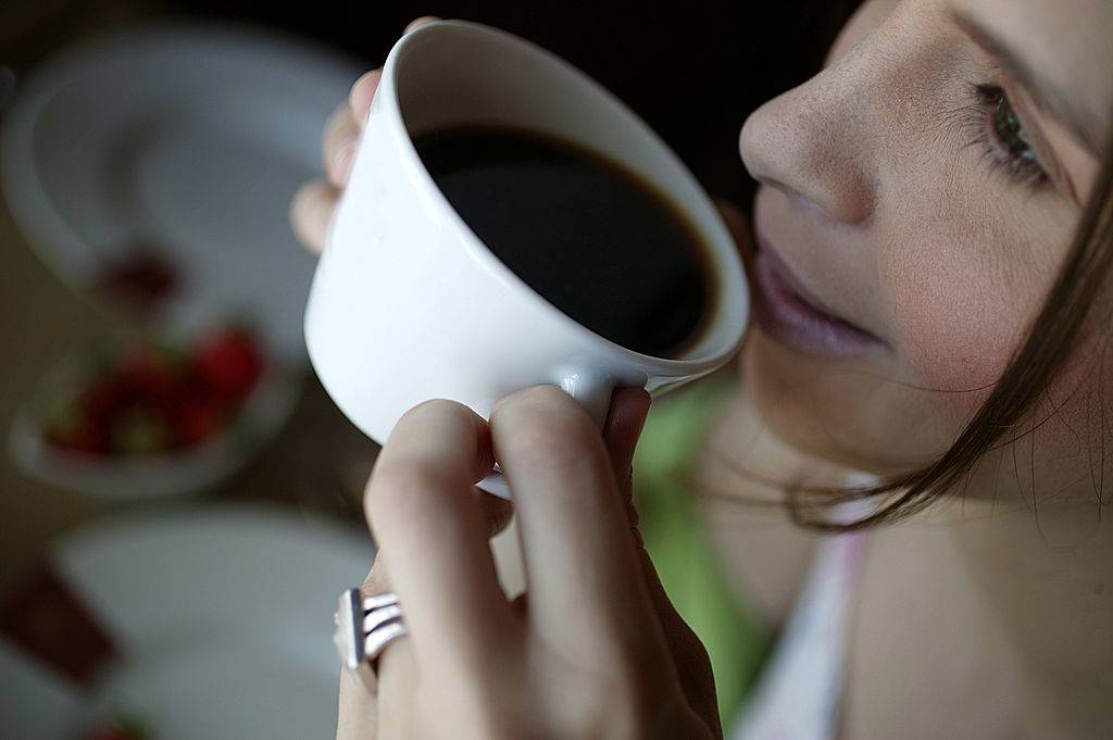 Close-up of a woman drinking a cup of black coffee