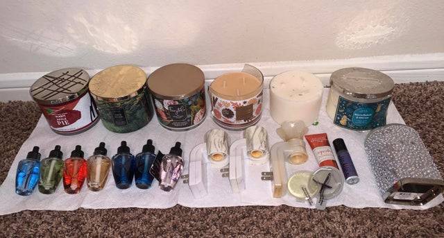 Candles and air fresheners laid out on the ground on a blanket.