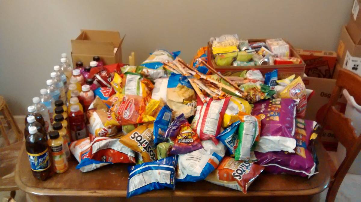 Chips and pop stacked on a table. 
