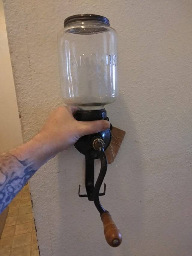 Old coffee grinder being held up. 