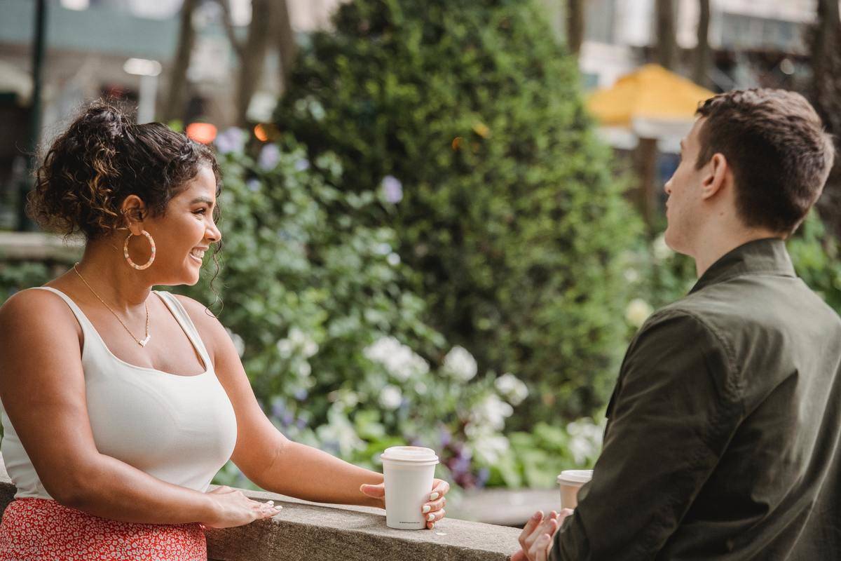 Two people chat over coffee outside