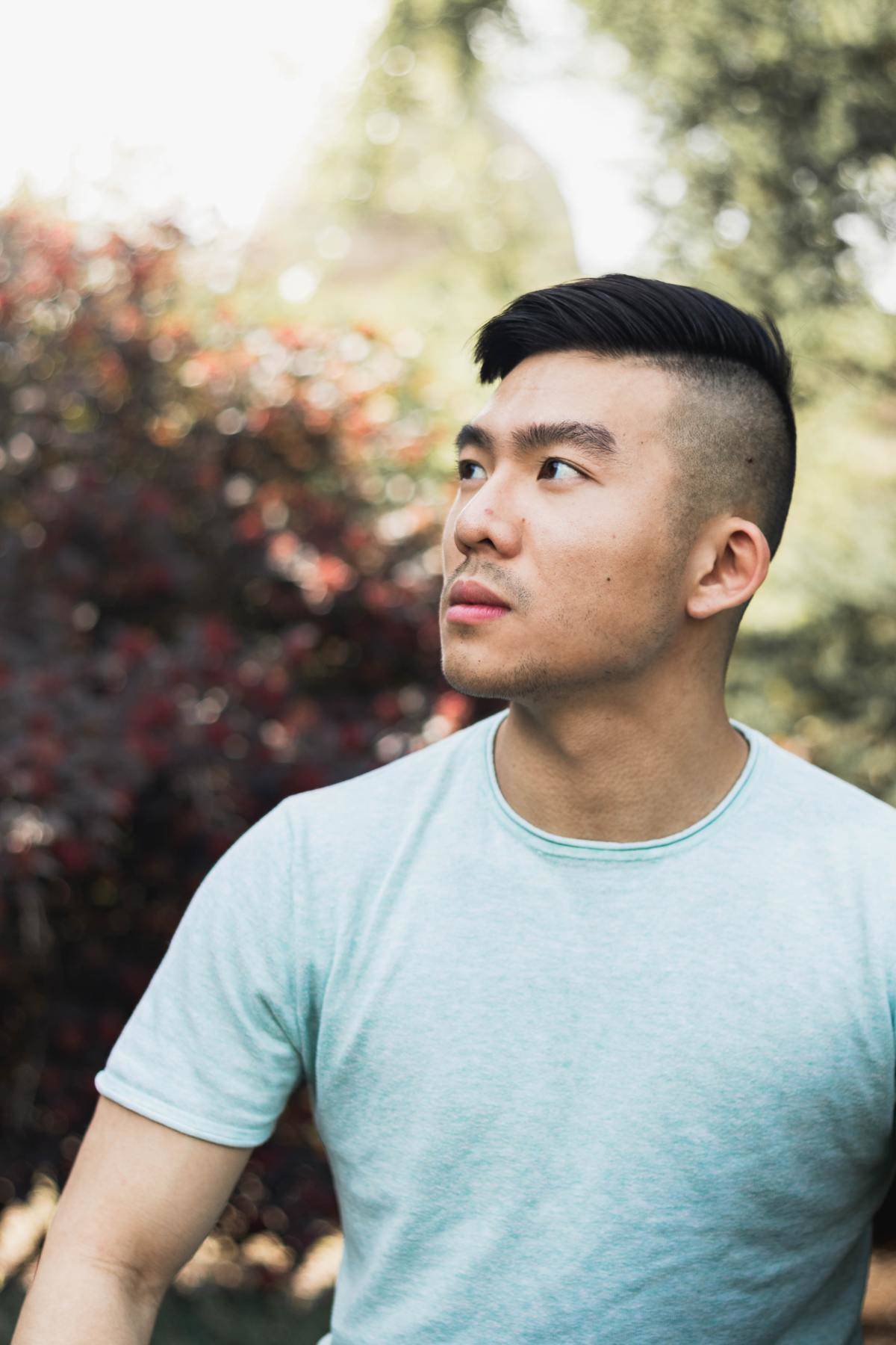 A man looks off-camera while posing outside.