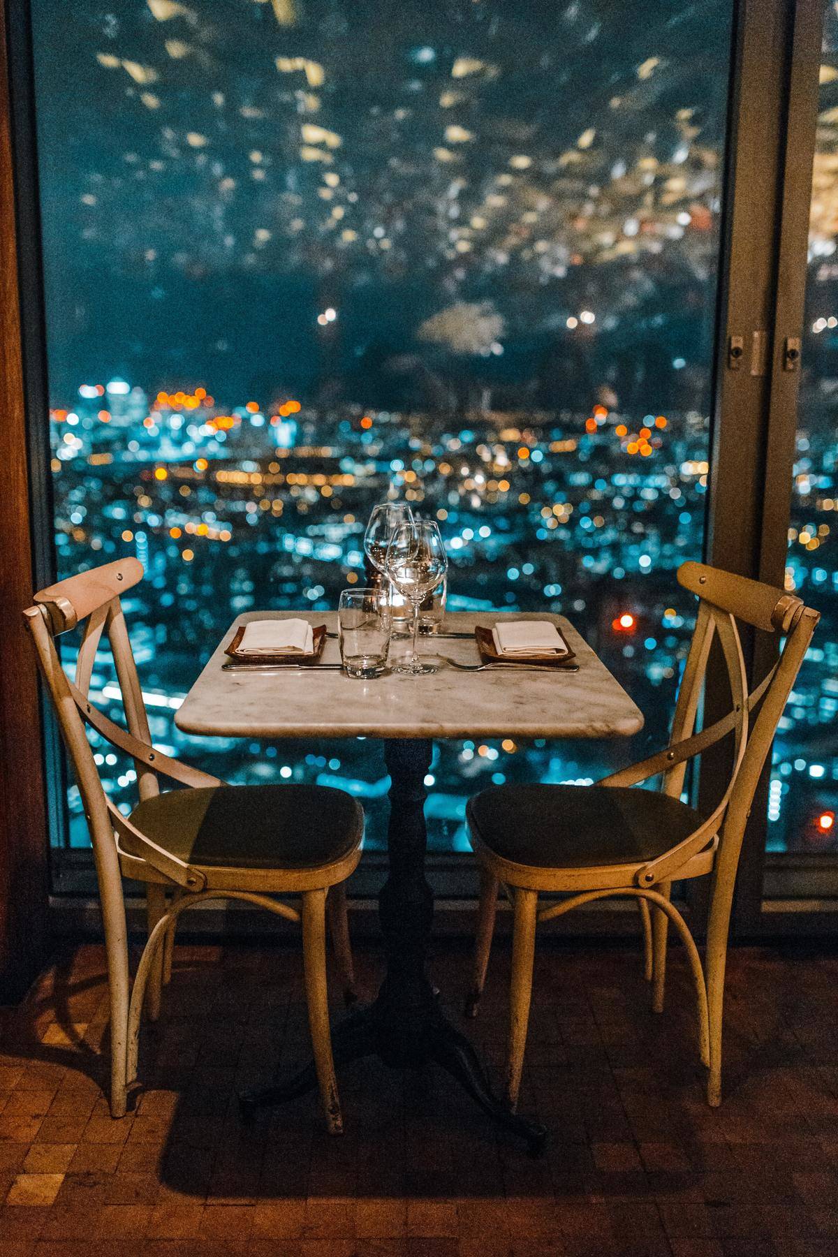 Table for two at a restaurant that overlooks the city lights below.