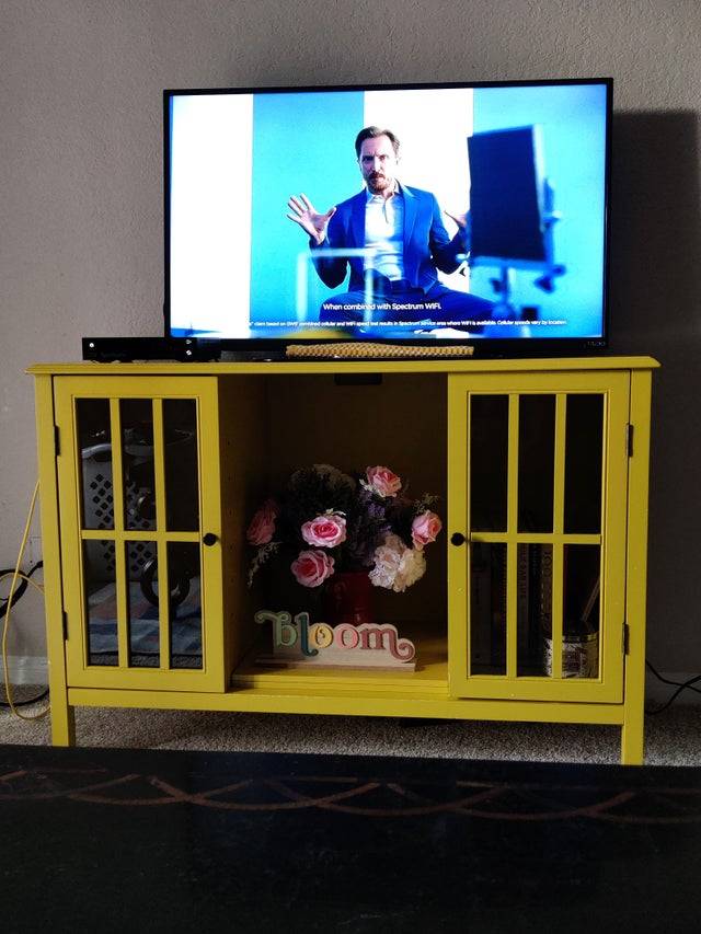 Yellow TV stand with a TV on top of it. 