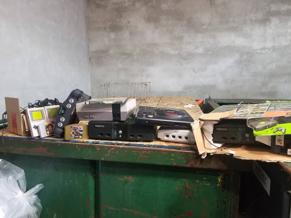 Old video game consoles on a dumpster. 