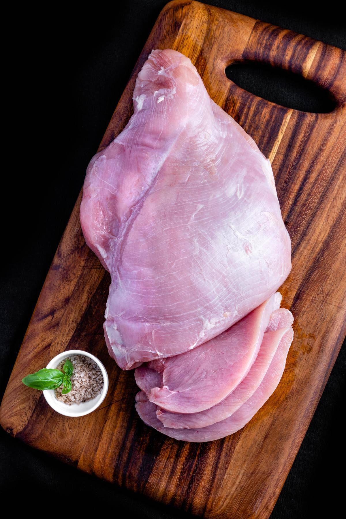 Raw chicken breast on a cutting board.