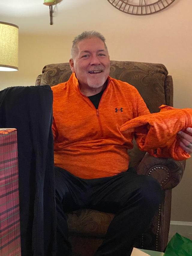 A dad receives an orange shirt for Christmas which is the exact one he's currently wearing.
