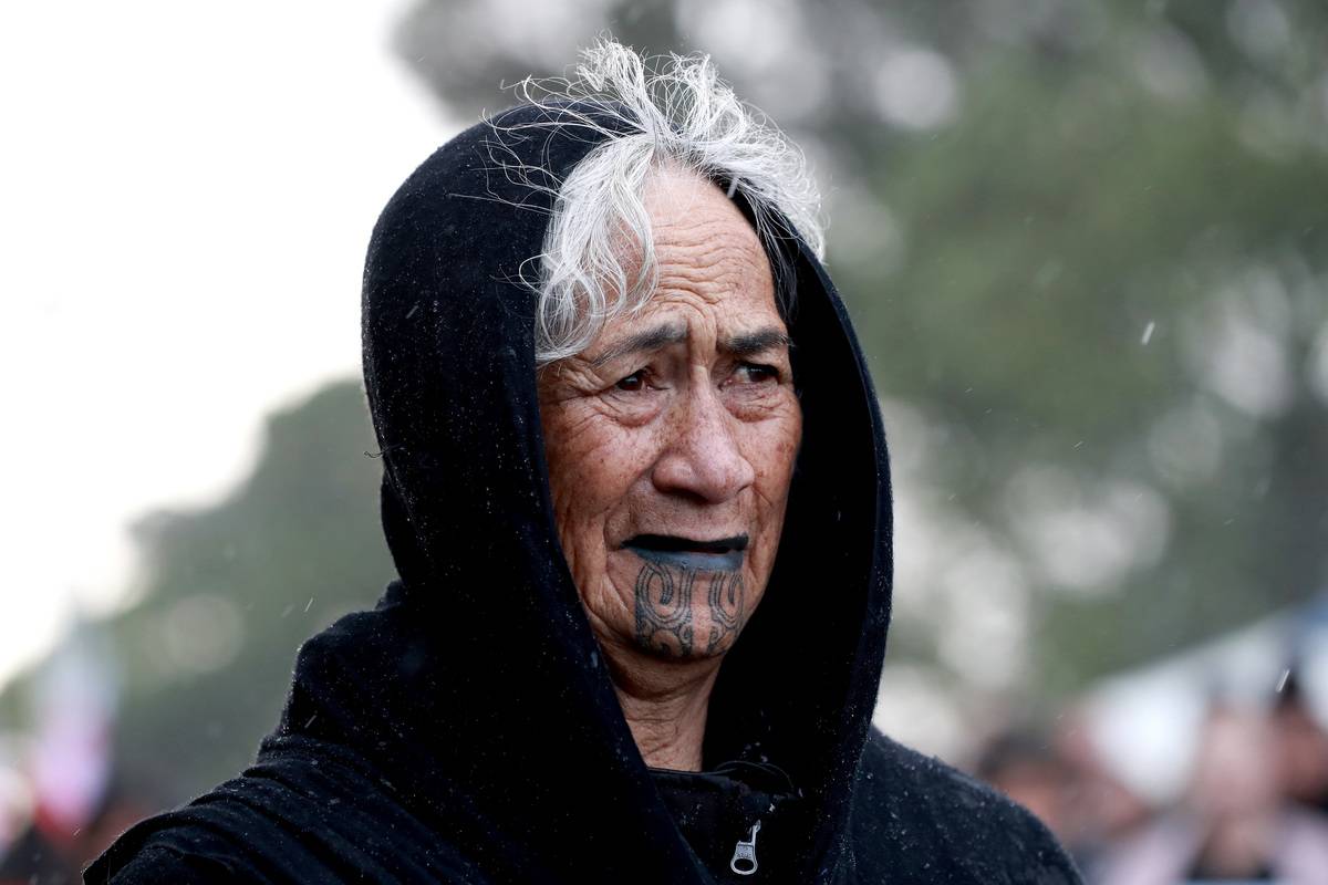 Older woman with tattoo under her chin and wearing a hood.