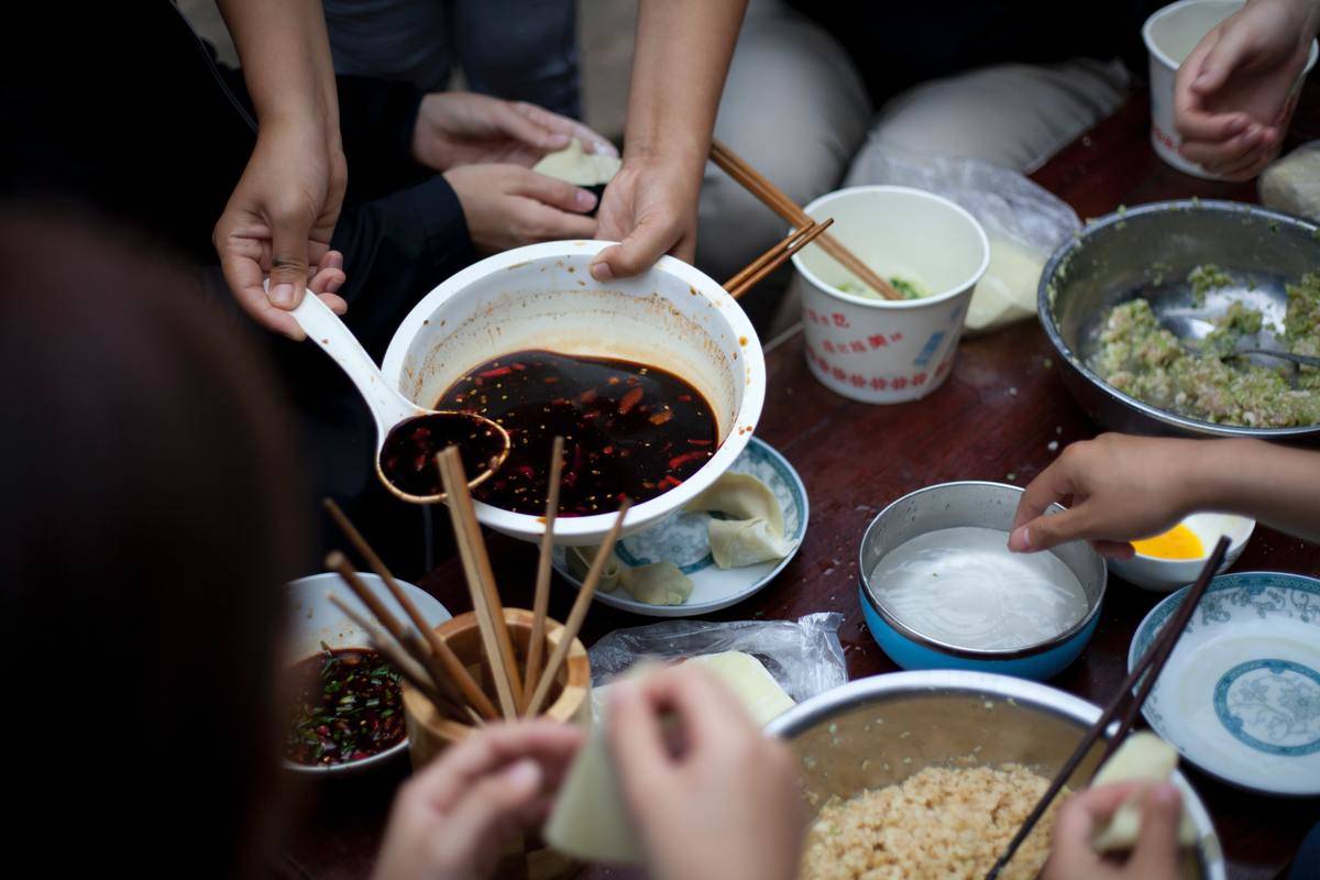 Asian food with many people reaching into the table.