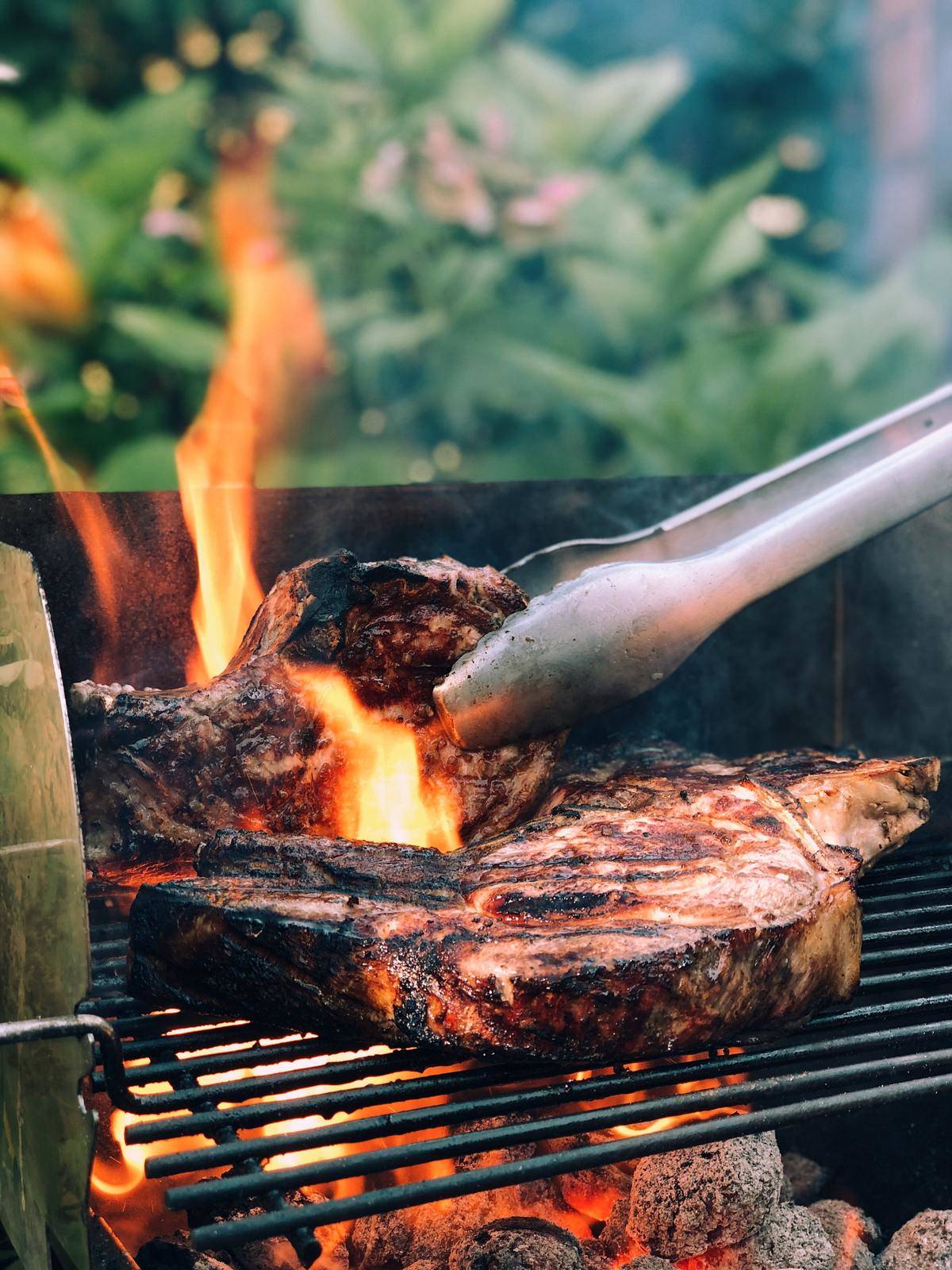 Steaks being cooked over a charcoal grill.