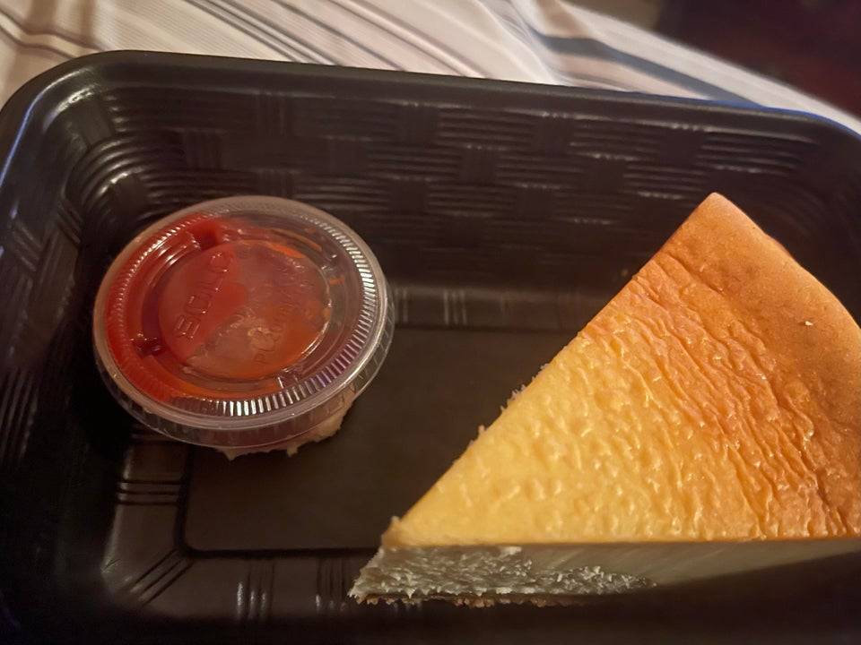 Cheesecake slice with ketchup in ramekin container