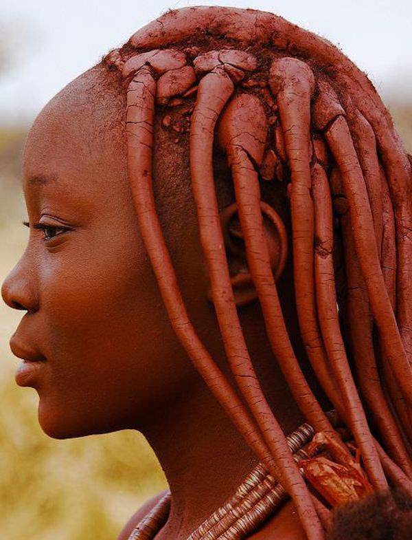 Woman with red clay in her hair and on her face. 